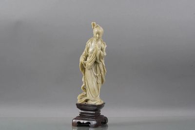 une figurine en ivoire représentant une femme tenant un oiseau, posée sur un socle