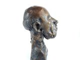 a bronze sculpture of a man ' s head on a white surface
