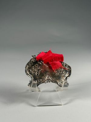 éléphant argenté avec un nœud rouge sur la tête, posé sur un socle en acrylique transparent