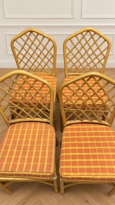 four vintage rattan chairs with orange and yellow plaid cushions