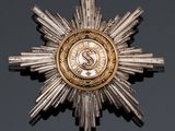 a silver and gold star brooch on a black surface