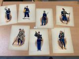 six reproductions d'uniformes militaires sont exposées sur une table