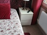 un lit avec des oreillers rouges et une table de chevet blanche sur laquelle est posée une lampe