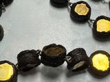 a black and gold necklace on a table next to a pair of scissors