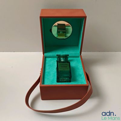a small bottle of perfume in a box on a table