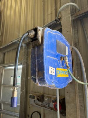 un réservoir bleu auquel est raccordé un tuyau, à l'intérieur d'un bâtiment