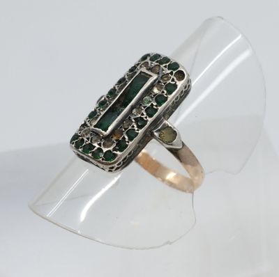 un gros plan d'une bague en argent sertie de pierres vertes