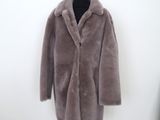 the coat is on a mannequin stand in front of a white wall