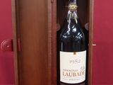 a bottle of wine in a wooden box on a red surface