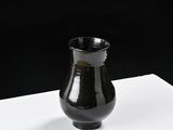 a small black vase sitting on a white surface