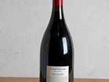 a bottle of red wine sitting on a wooden table