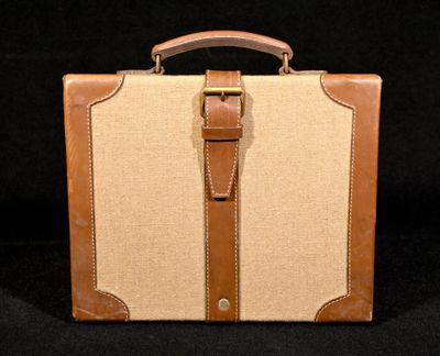 une valise marron et beige posée sur une surface noire
