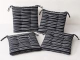 quatre coussins rayés noir et blanc posés sur une surface blanche