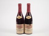 deux bouteilles de vin rouge posées l'une à côté de l'autre sur une surface blanche