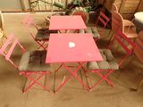 une table et des chaises roses, sur lesquelles est posé un ordinateur portable Apple