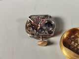 a small watch with a gold ring on a table
