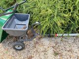 a wheelbarrow with a bucket attached to it next to a bush