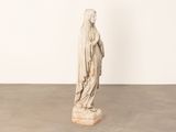 une statue représentant une femme portant un voile sur la tête, dans une pièce blanche