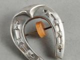 a close up of a silver brooch with a wooden pin