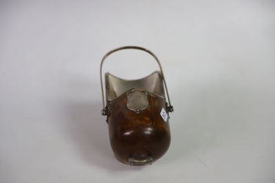 a small metal vase with a wooden handle on a white surface