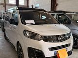 une camionnette blanche garée dans un garage à côté d'autres voitures
