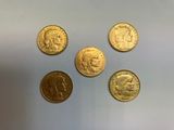 quatre types différents de pièces d'or reposant sur une surface blanche