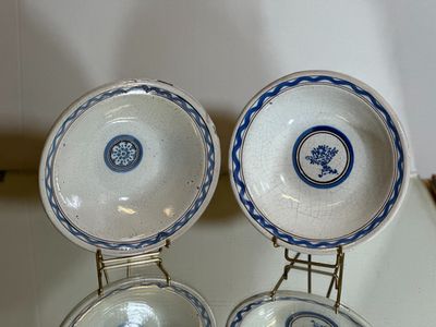 trois assiettes bleues et blanches sont posées sur un présentoir posé sur une table