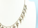 a silver necklace with pink stones on a mannequin