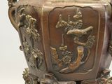 a bronze vase on a stand on a white surface