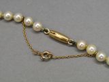 un gros plan d'un collier composé de perles montées sur une chaîne en or