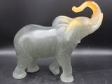 a glass elephant that is standing on a black surface