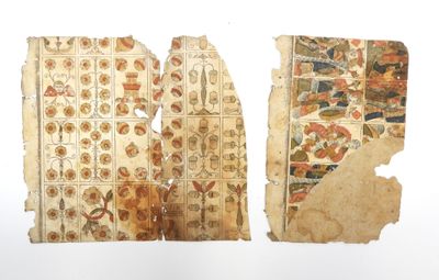 deux morceaux de vieux papier comportant des motifs, posés sur une surface blanche