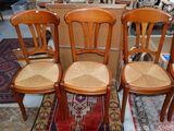 Trois chaises en bois aux assises tressées sont posées sur un tapis dans une pièce