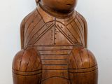 a wooden statue of a man sitting on a stool