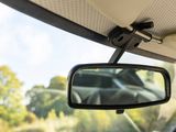 a rear view mirror of a car with a view of trees in the background