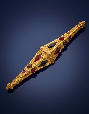 Gros plan sur une broche en or et rubis sur fond bleu