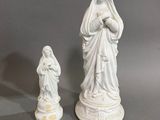 deux statues blanches représentant Jésus et Marie sur un fond gris