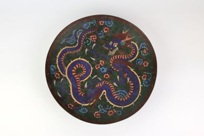 a decorative plate with a dragon on it on a white surface