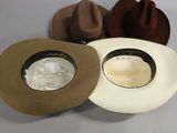 several hats are lined up on a table with a white cloth