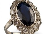 une image représentant une bague ornée d'une grosse pierre noire entourée de petits diamants blancs