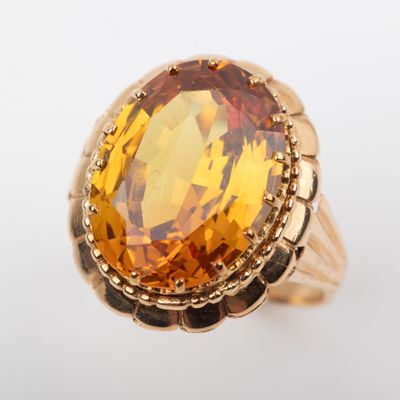 a close up of a gold ring with a large citrine stone