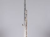 an old silver flute with a flute stand on a grey background