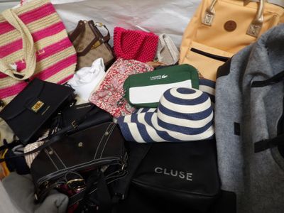 a pile of purses and handbags sitting on a bed