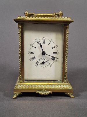 a small gold clock with roman numerals on it