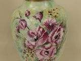 a green vase with pink flowers on it and a gold lid