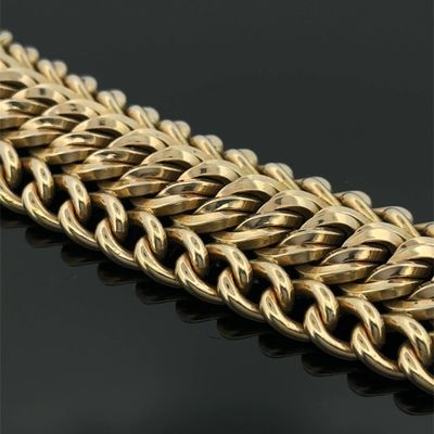 a close up of a gold chain bracelet on a black surface
