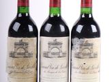 trois bouteilles de vin rouge sont alignées sur une surface blanche