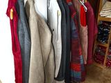 many sweaters hanging on a rack in a room