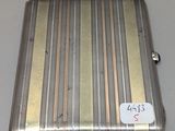 un vieux étui à cigarettes en argent posé sur une table