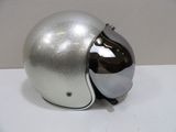 un casque argenté muni d'une visière argentée, posé sur une table blanche
